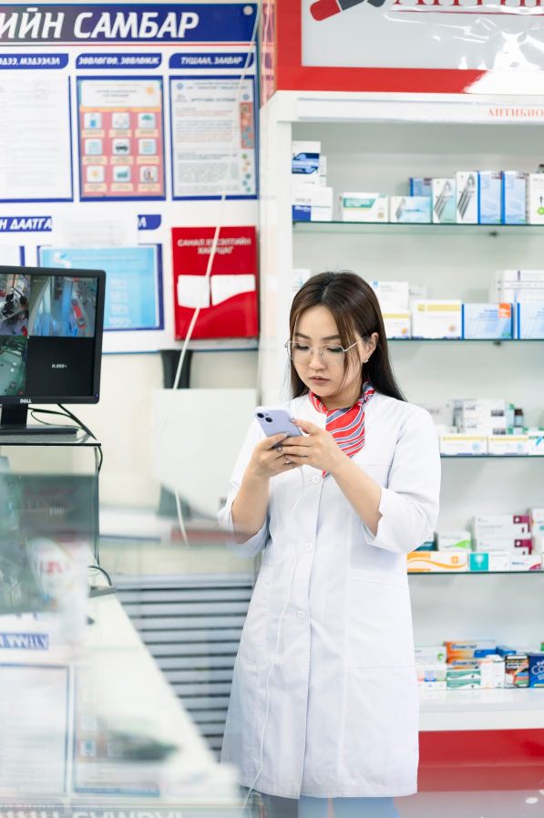 Farmacêutica no ponto de venda consultando o celular